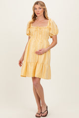 woman wearing a yellow striped maternity dress with a square neckline and puff sleeves, showing her baby bump