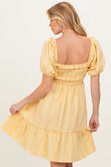 woman wearing a yellow striped maternity dress with puff sleeves and a smocked bodice, showing her back