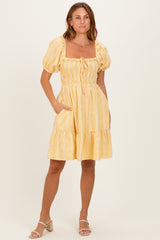 woman wearing a yellow striped puff sleeve dress with a square neckline and pockets