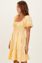 woman wearing a yellow gingham puff sleeve mini dress with smocked bodice and ruffled hem