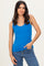 woman wearing a bright blue ribbed tank top and distressed jeans, posing with one hand on her hip