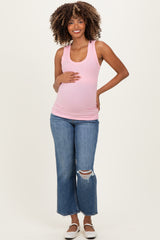 woman wearing a light pink ribbed maternity tank top and distressed flared jeans, holding her baby bump