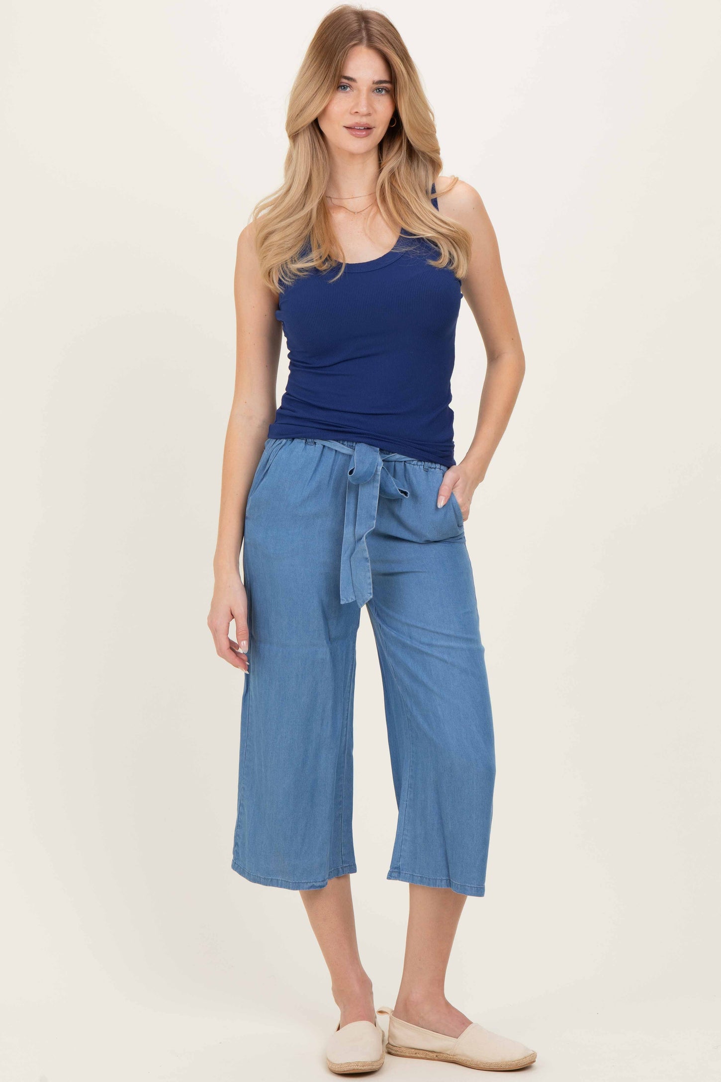 woman wearing a navy blue ribbed tank top and light blue cropped wide-leg pants with a tie waist detail