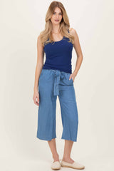 woman wearing a navy blue ribbed tank top and light blue cropped wide-leg pants with a tie waist detail