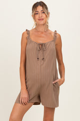 woman wearing a brown striped maternity romper with ruffle straps and a tie front detail