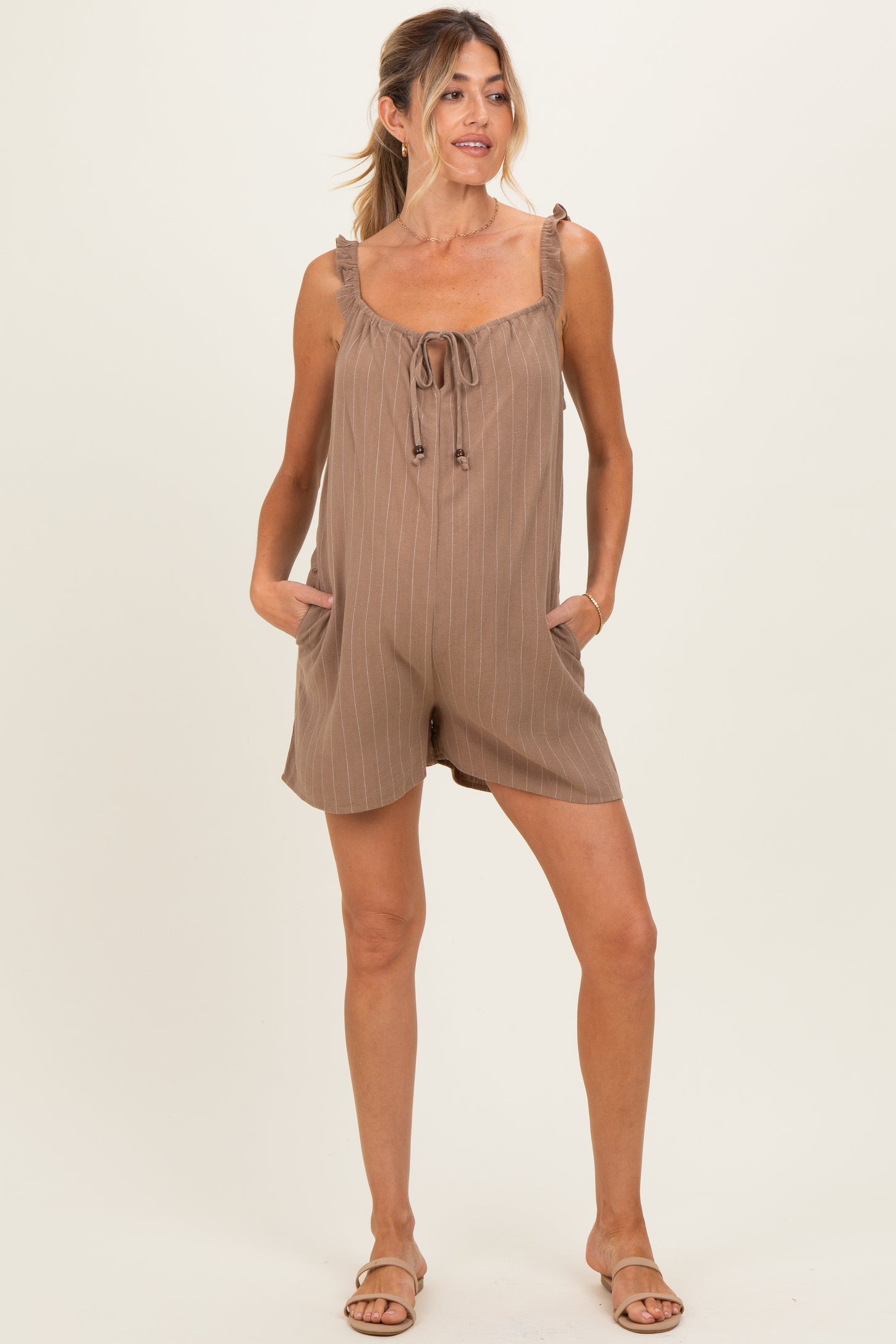 woman wearing a brown striped maternity romper with tie straps and pockets