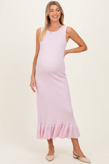 woman wearing a light pink ribbed maternity maxi dress with a ruffled hem and a visible baby bump