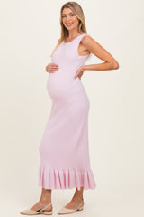 woman wearing a light pink ribbed maternity dress with a ruffled hem and showing her baby bump