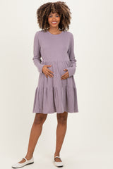woman wearing a purple striped maternity dress with long sleeves and a tiered skirt, holding her baby bump