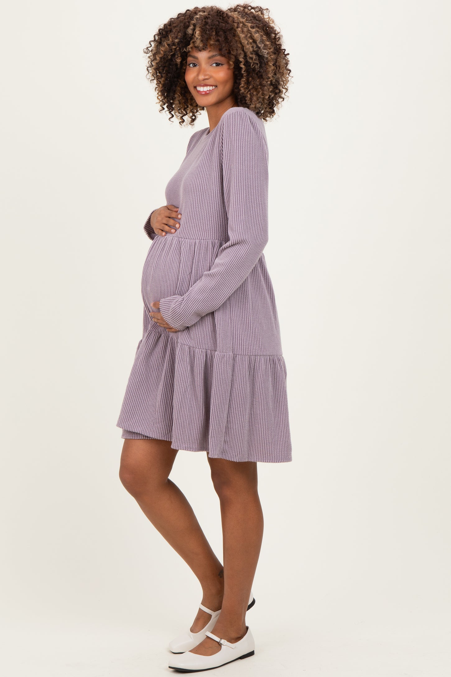 woman wearing a lavender striped maternity dress with a tiered skirt and holding her baby bump