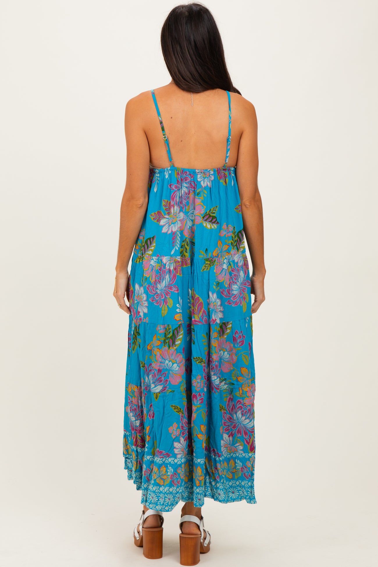 woman wearing a turquoise floral maxi dress with spaghetti straps, seen from the back