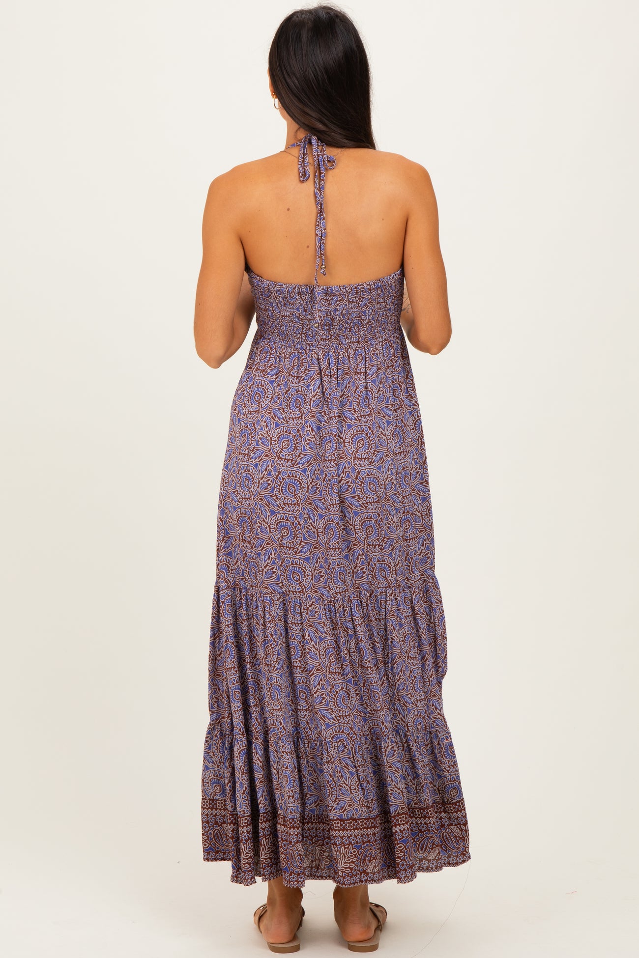 woman wearing a strapless purple printed maxi dress with smocked bodice and tiered skirt, seen from the back