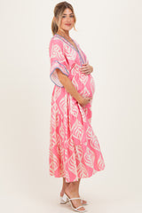 woman wearing a pink floral maternity maxi dress and holding her baby bump