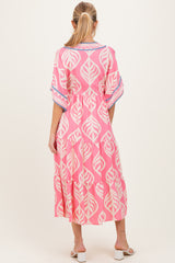 woman wearing a pink maternity dress with a leaf print and tiered skirt, seen from the back