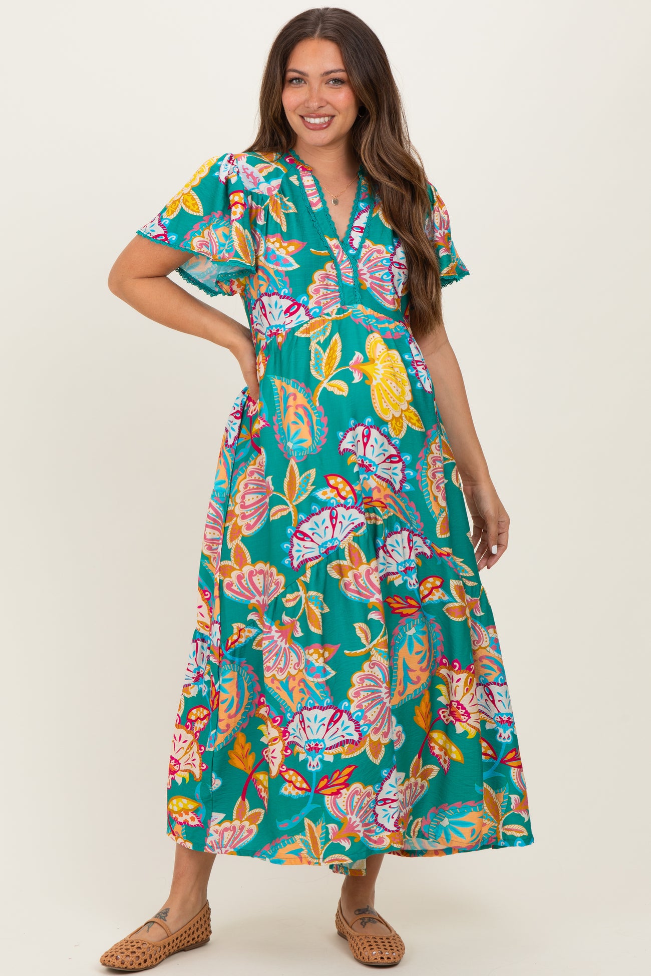 woman wearing a vibrant floral maternity maxi dress with short sleeves and a v-neckline, showcasing her baby bump