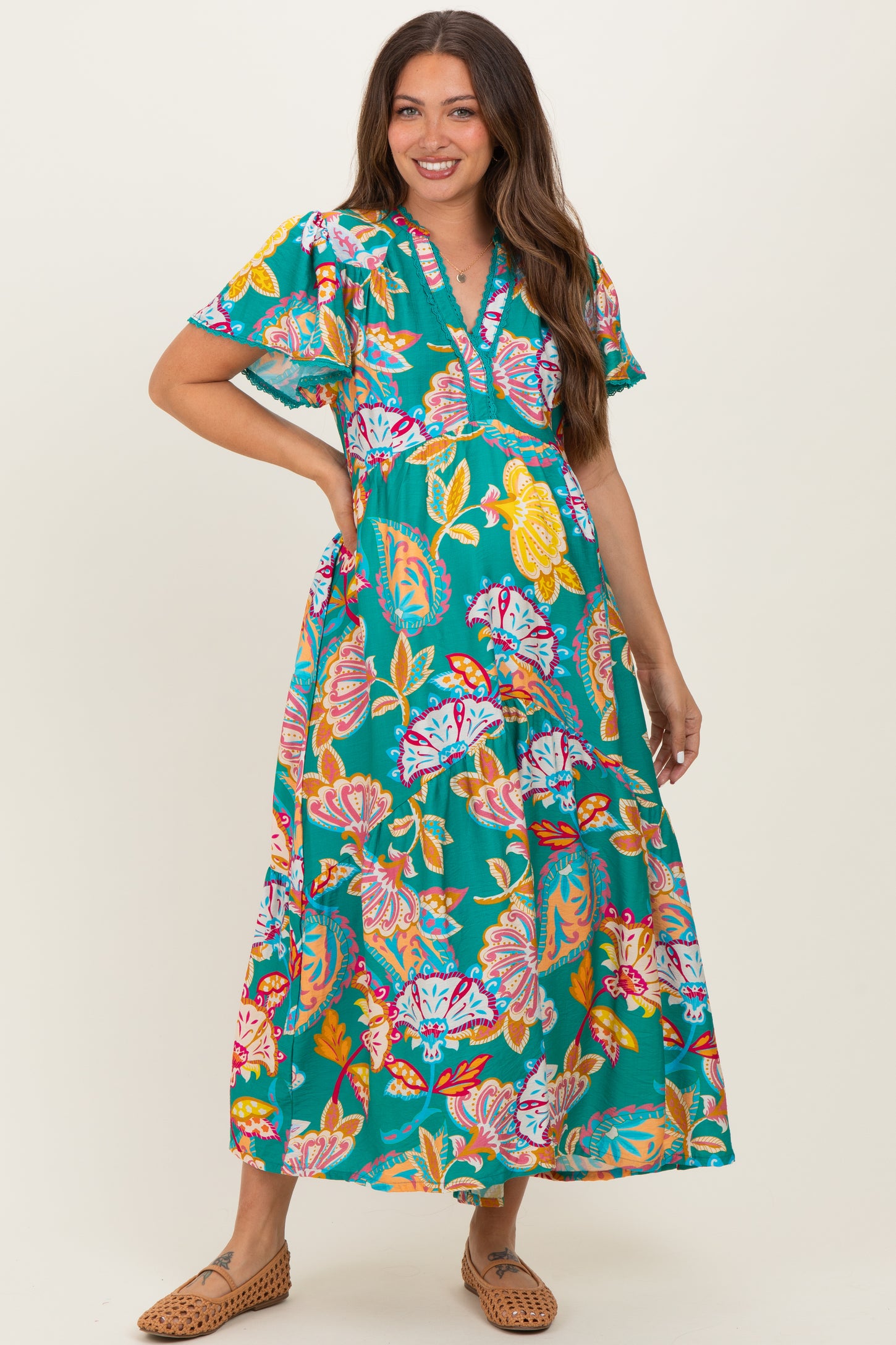 woman wearing a vibrant floral maternity maxi dress with short sleeves and a v-neckline, showcasing her baby bump