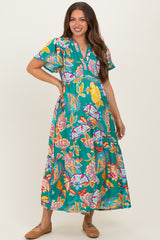 woman wearing a vibrant floral maternity maxi dress with short sleeves and a v-neckline, showcasing her baby bump