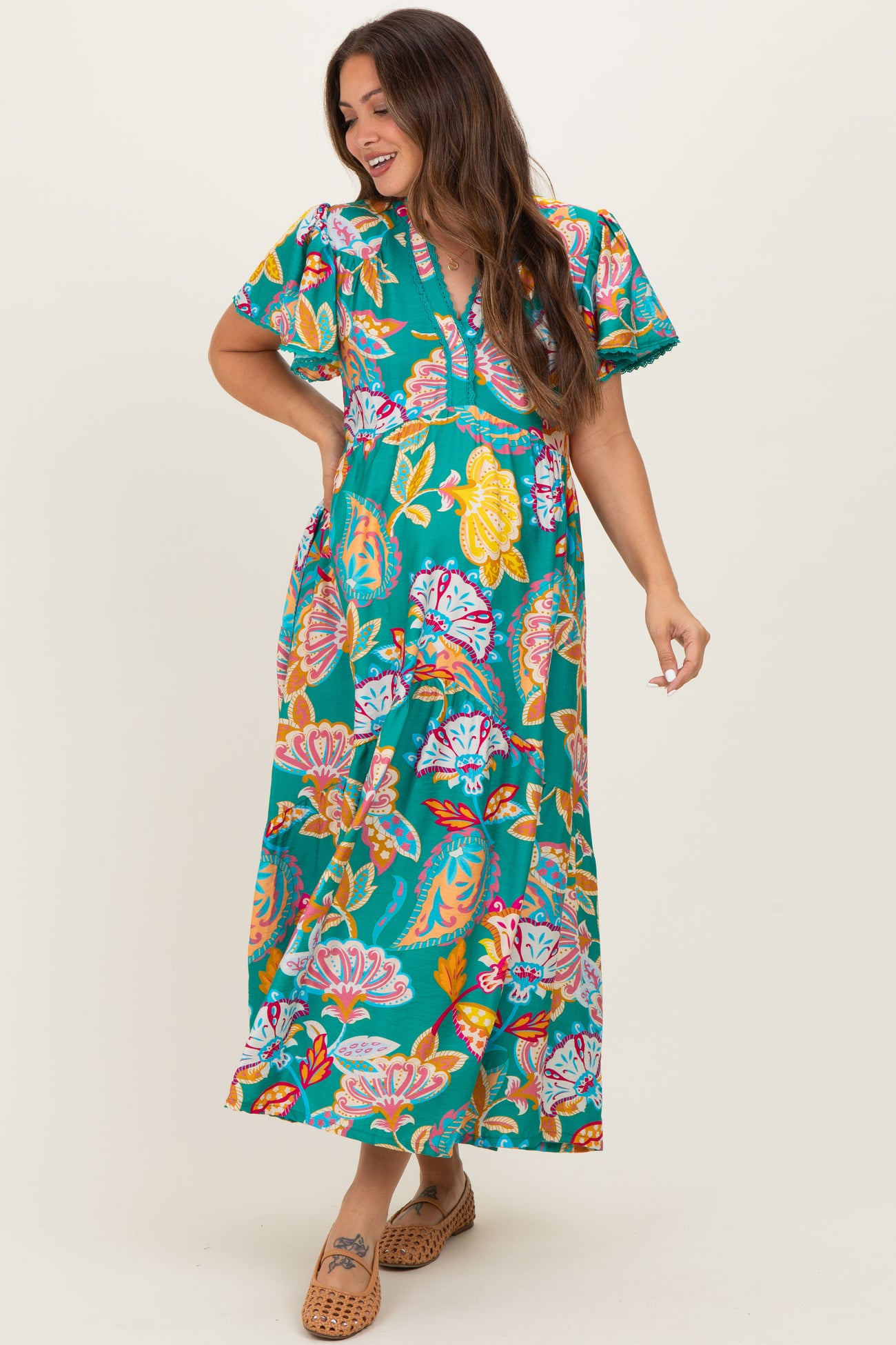 woman wearing a teal floral maternity maxi dress with short sleeves and a v-neckline