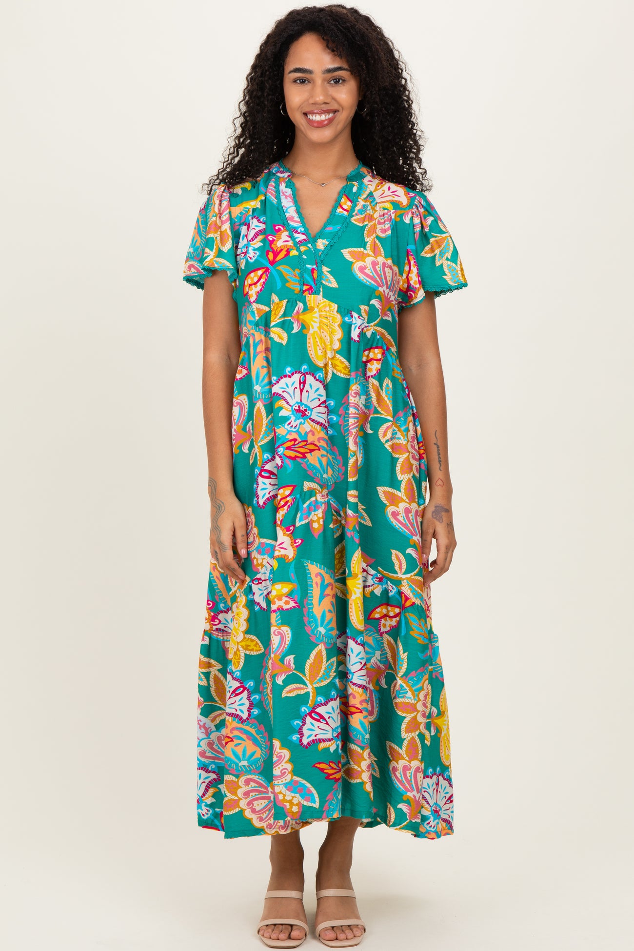 woman wearing a teal floral maxi dress with short sleeves and a button-up neckline