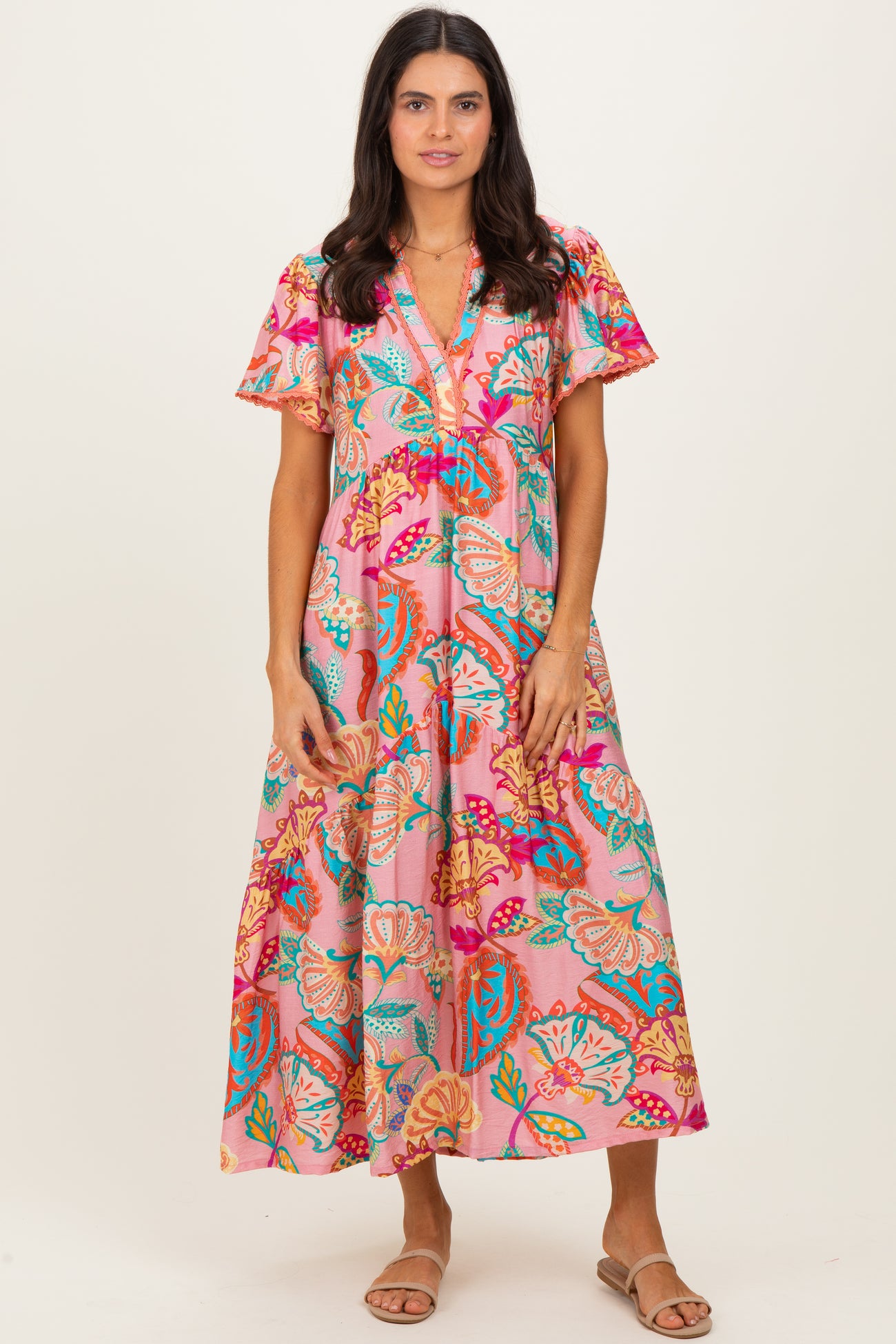 woman wearing a pink floral maxi dress with short flutter sleeves and v-neckline