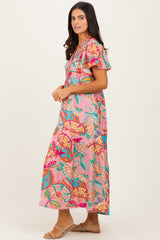 woman wearing a pink floral maxi dress with flutter sleeves and vibrant patterns