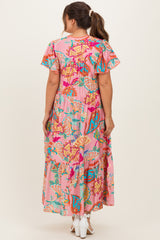 woman wearing a pink floral patterned maternity maxi dress with flutter sleeves and a tiered skirt