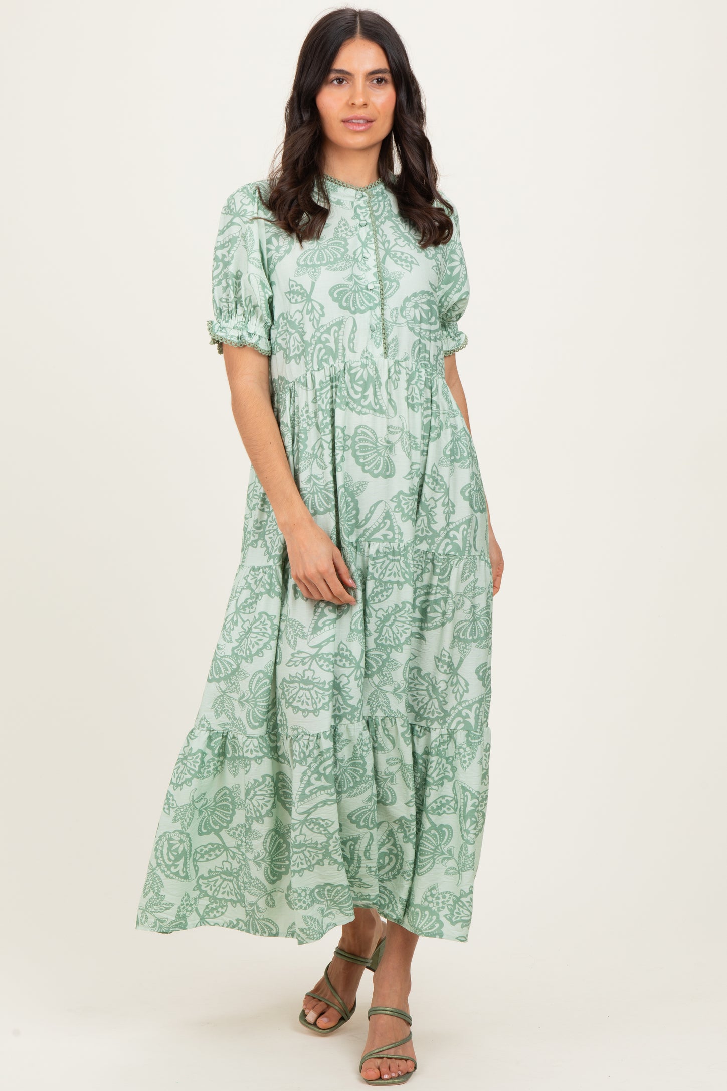 woman wearing a light green floral printed maxi dress with puff sleeves and a tiered skirt