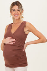 woman wearing a brown sleeveless maternity top and holding her baby bump