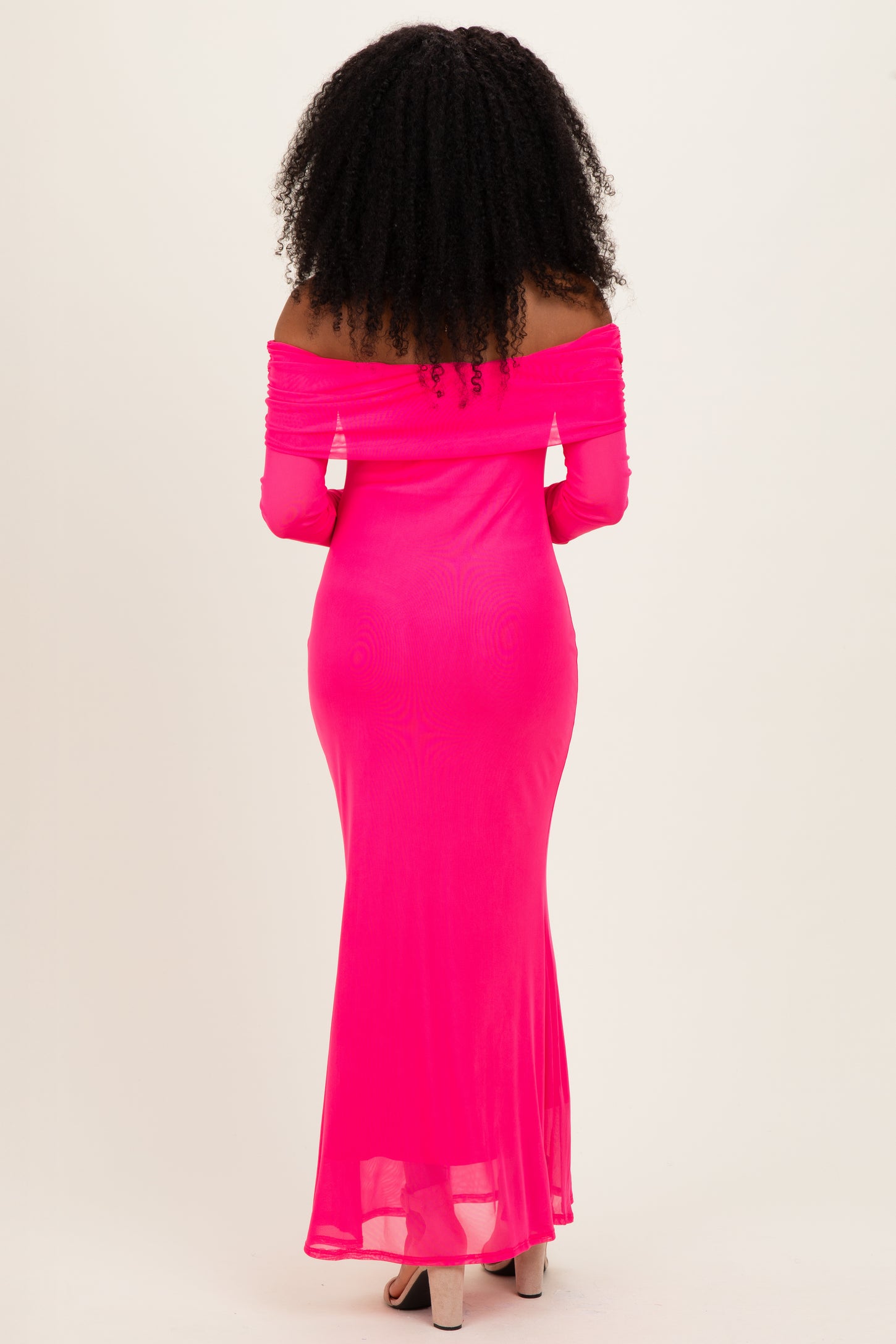 woman wearing a bright pink off-the-shoulder maxi dress with a fitted silhouette and long sleeves