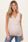 woman wearing a light beige maternity wrap tank top and showcasing her baby bump with a smile