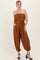 woman wearing a strapless brown jumpsuit with a drawstring waist and side pockets