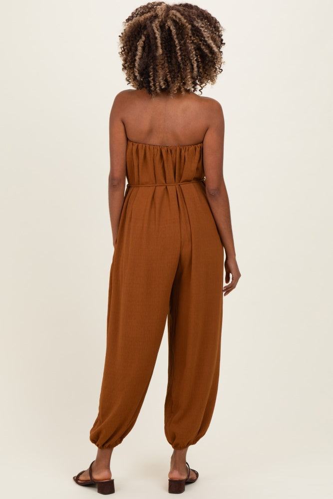woman wearing a brown strapless maternity jumpsuit with a relaxed fit and tapered legs, shown from the back