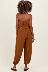 woman wearing a brown strapless maternity jumpsuit with a relaxed fit and tapered legs, shown from the back