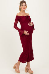 woman wearing a burgundy lace off-the-shoulder maternity gown and holding her baby bump