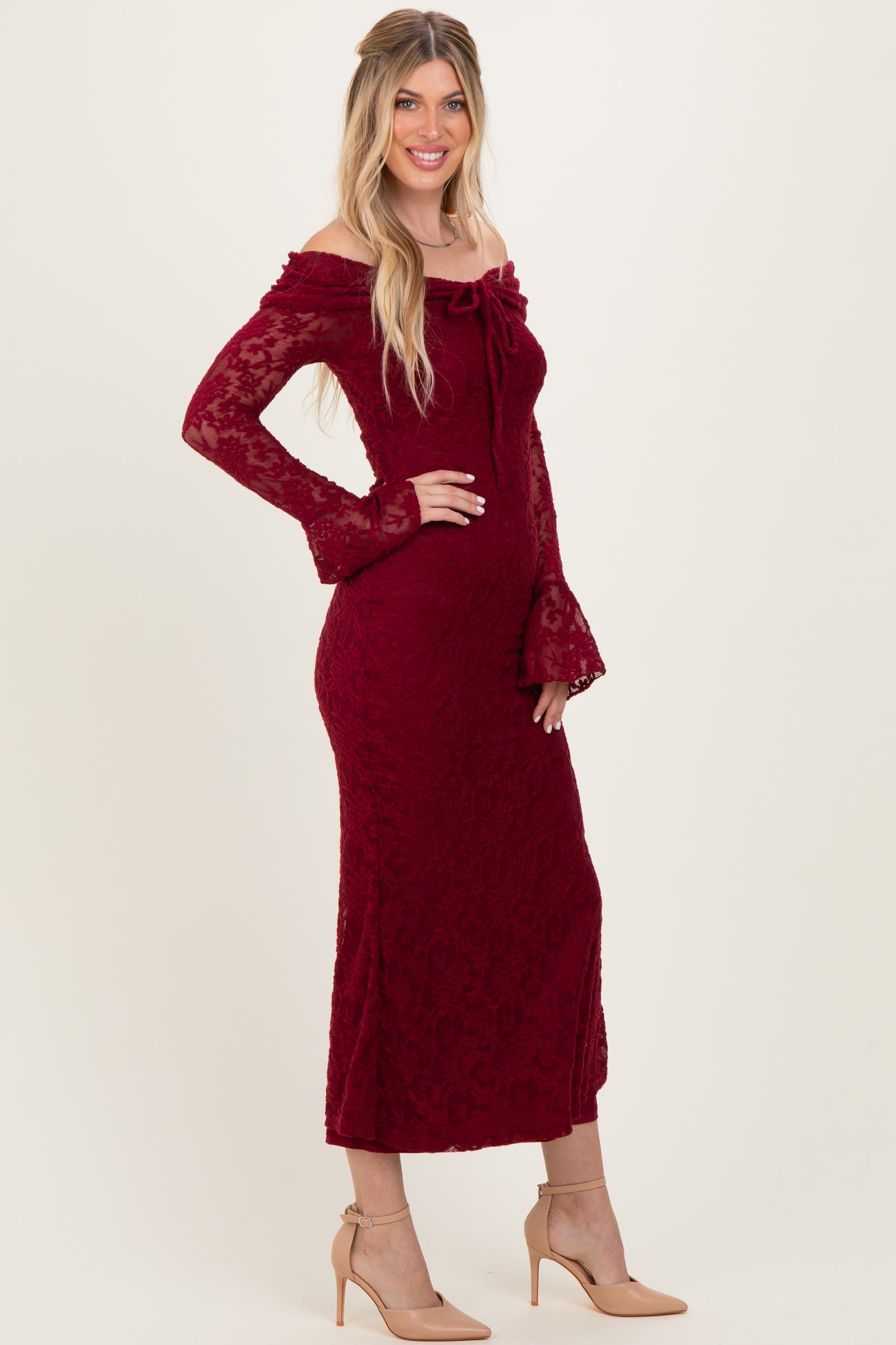 woman wearing a burgundy off-the-shoulder lace midi dress with bell sleeves and a front tie detail