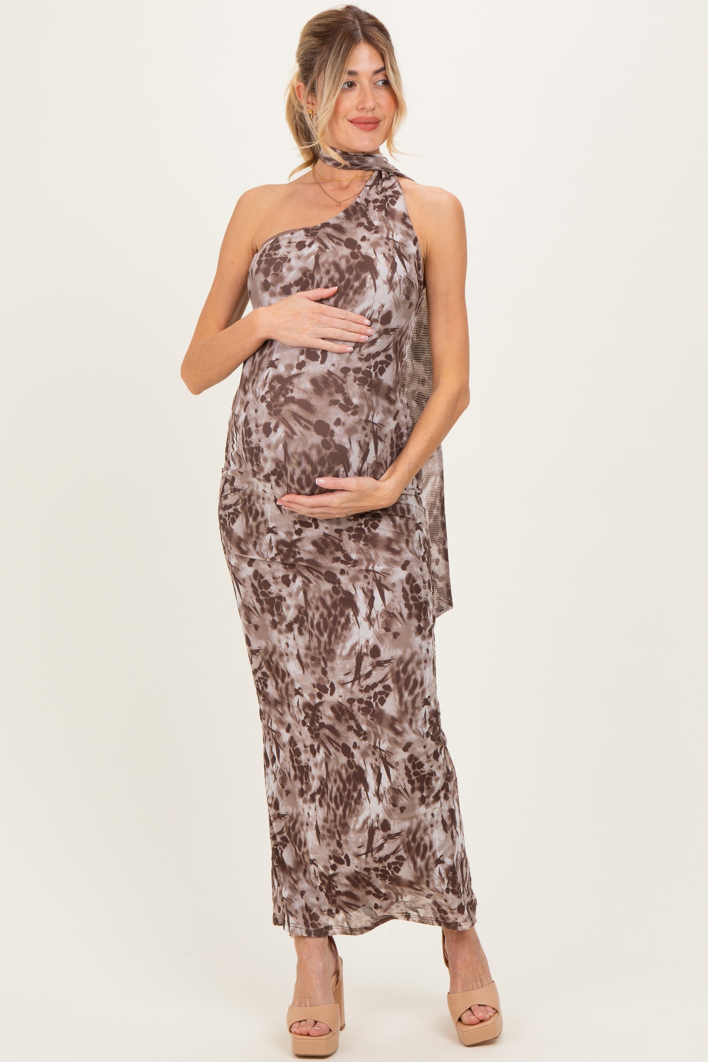 woman wearing a brown and cream floral print maternity dress with a halter neck, holding her baby bump