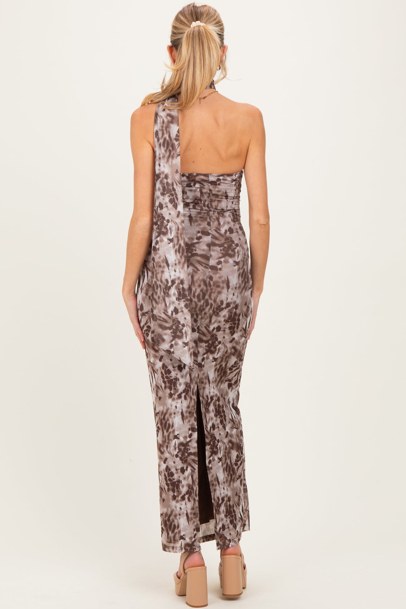woman wearing a brown tie-dye one-shoulder maternity dress with a side slit and form-fitting silhouette