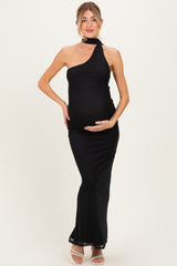 woman wearing a black one-shoulder maternity dress, showcasing her baby bump, standing elegantly with hands on her belly