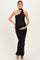 woman wearing a black one-shoulder maternity dress, showcasing her baby bump, standing elegantly with hands on her belly
