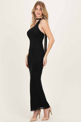woman wearing a black sleeveless maxi dress with a high neckline and back tie detail