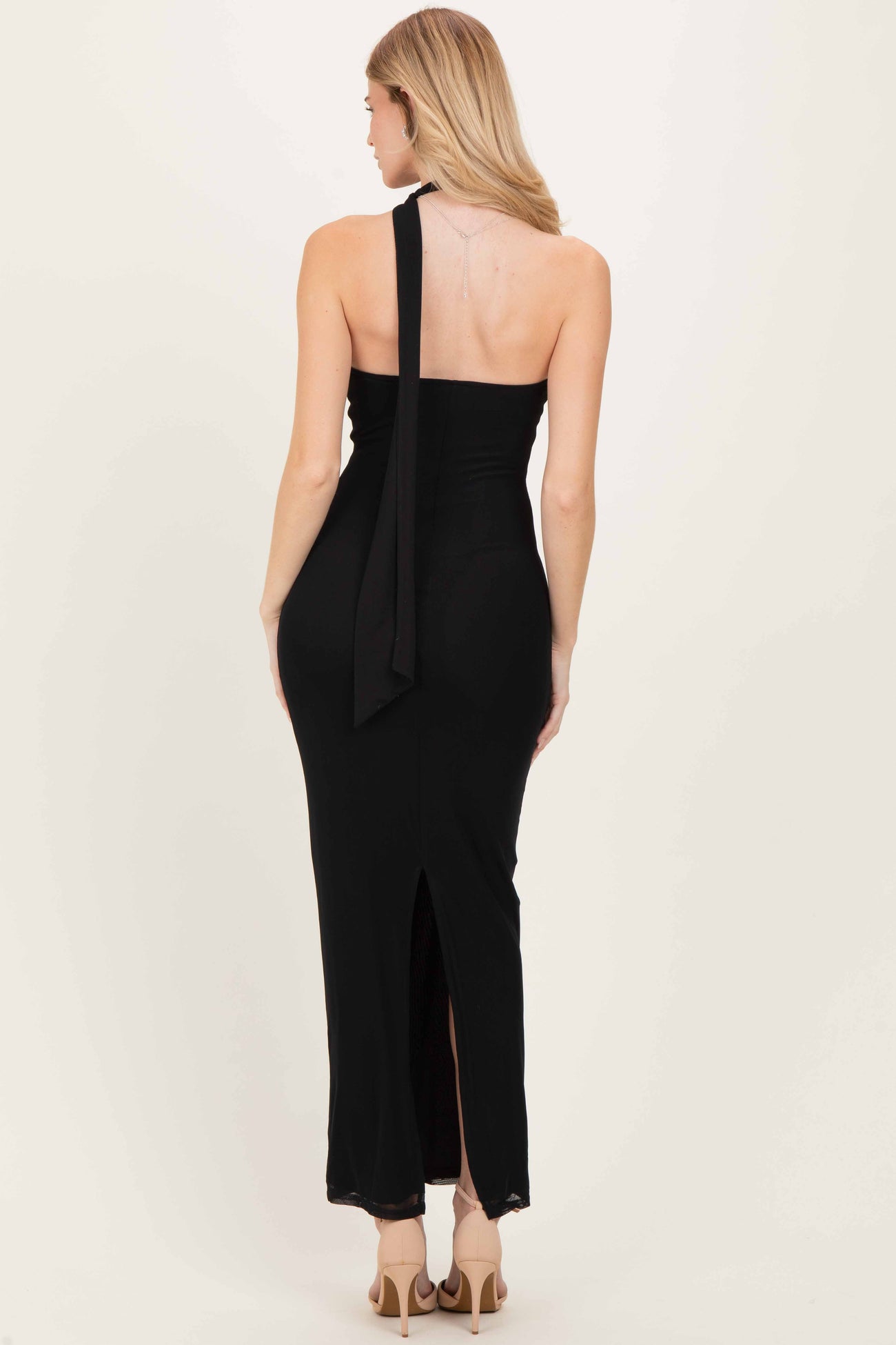 woman wearing a black halter neck maxi dress with a back tie detail and side slit