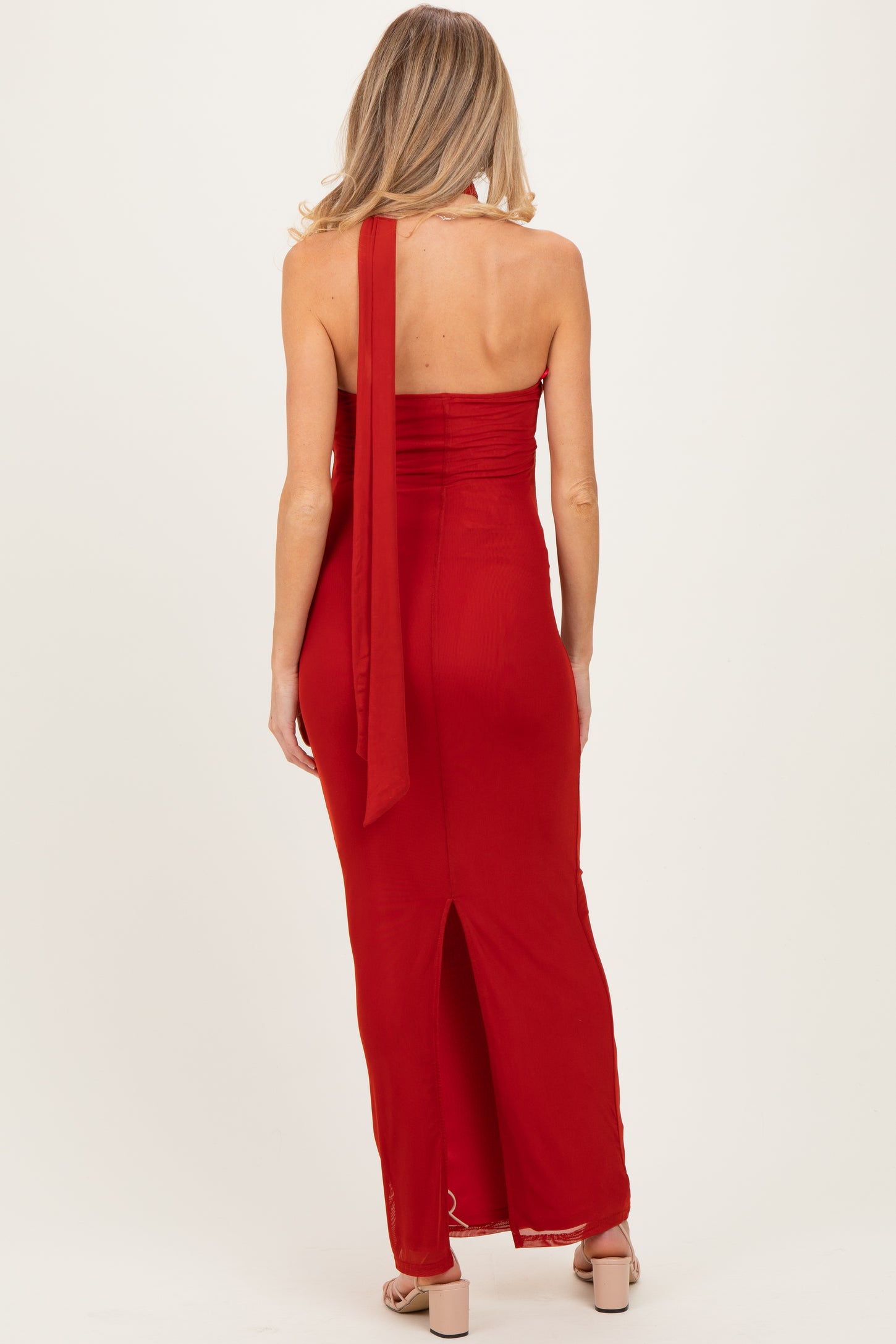 woman wearing a red maternity maxi dress with a halter neck and side slit from the back