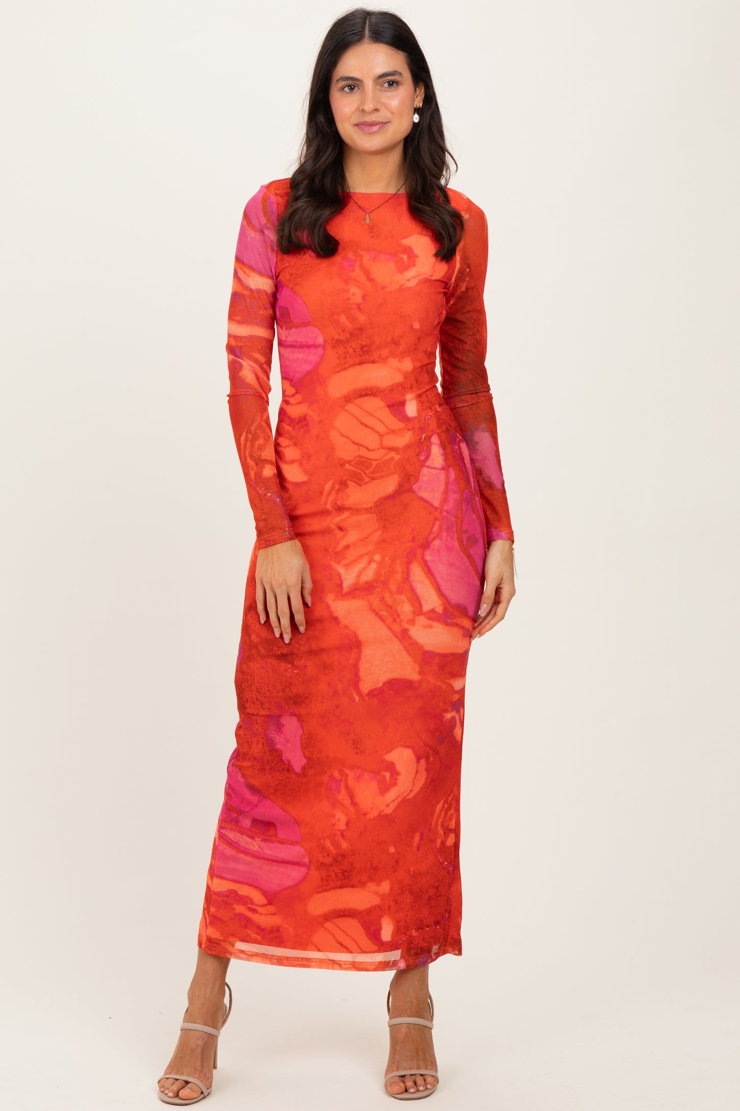 woman wearing a long sleeve red maxi dress with abstract orange and pink patterns