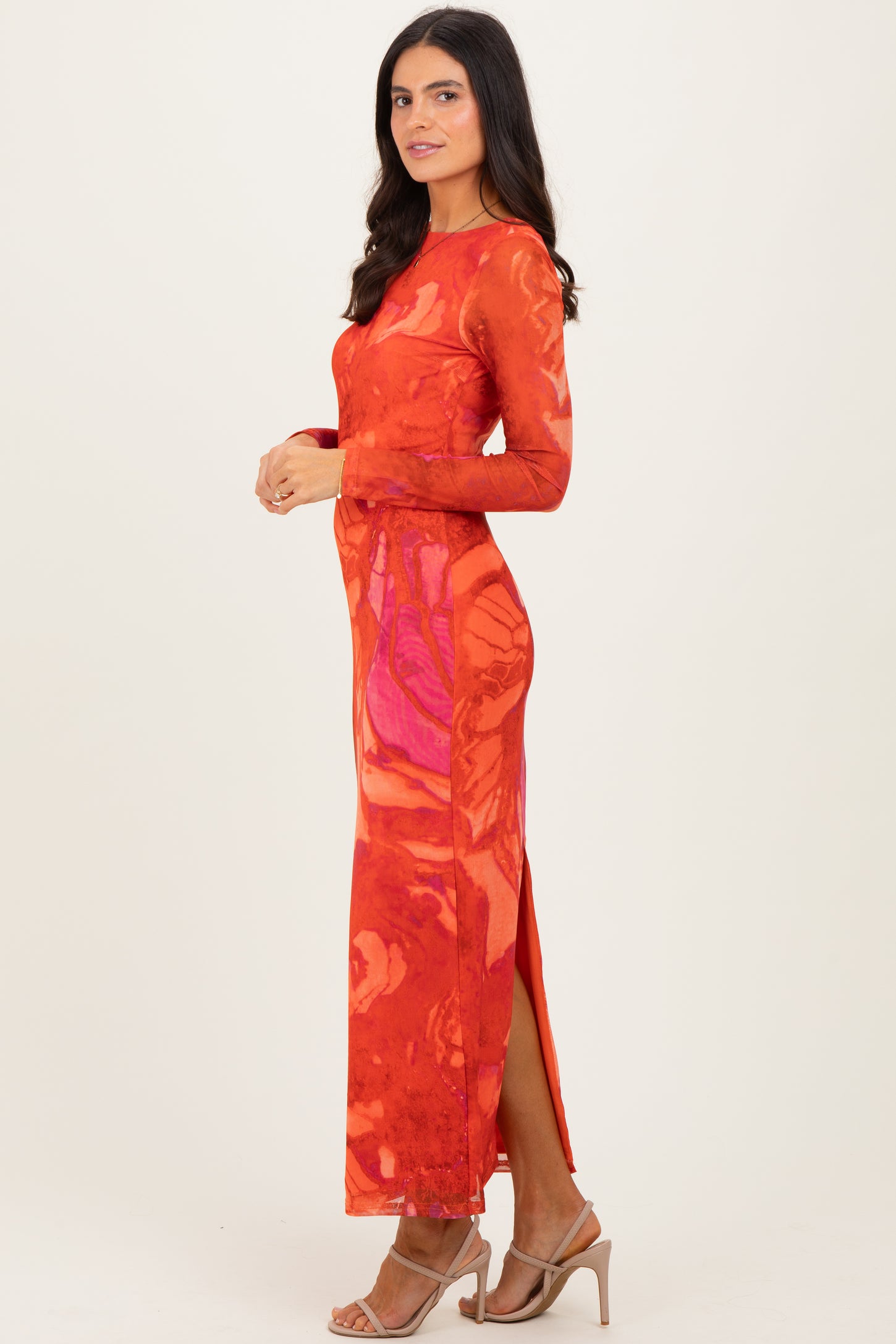 woman wearing a long sleeve red floral maxi dress with side slits and a fitted silhouette