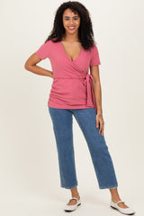 woman wearing a pink wrap top with a tie detail and short sleeves, paired with light blue straight-leg jeans