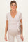 woman wearing a beige maternity wrap top with short sleeves and a side tie, showcasing her baby bump