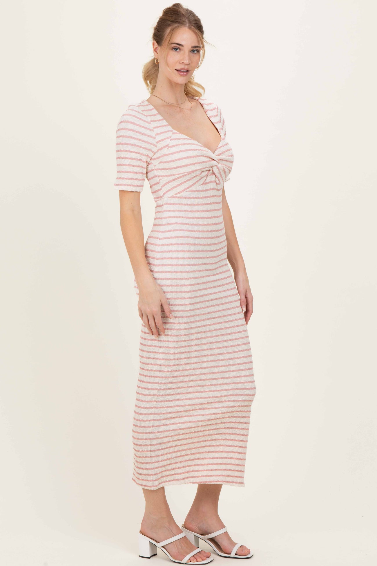 woman wearing a pink and white striped midi dress with short sleeves and a knotted detailing at the bust
