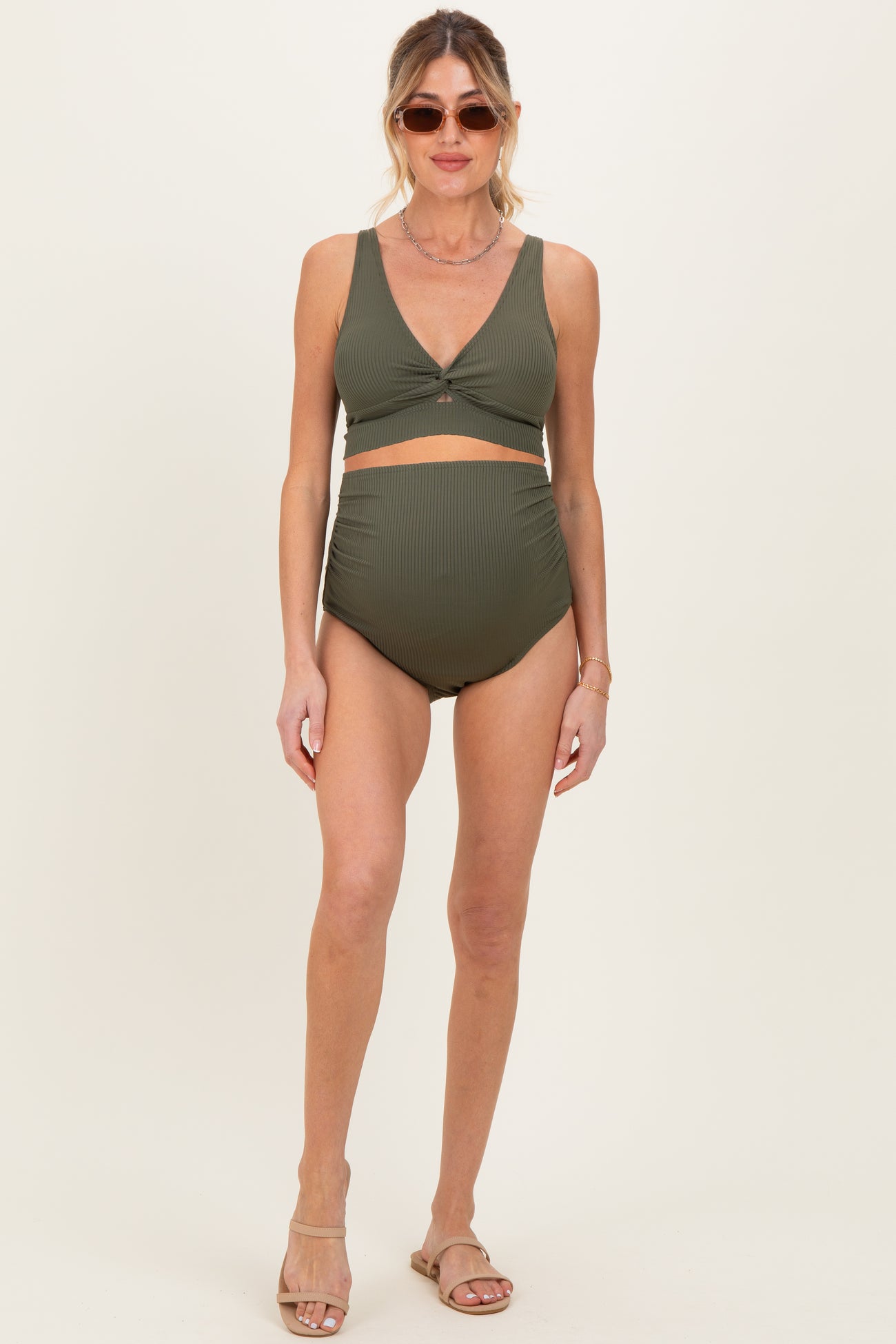 woman wearing an olive green ribbed maternity bikini with a twist front top and high-waisted bottom, showing her baby bump