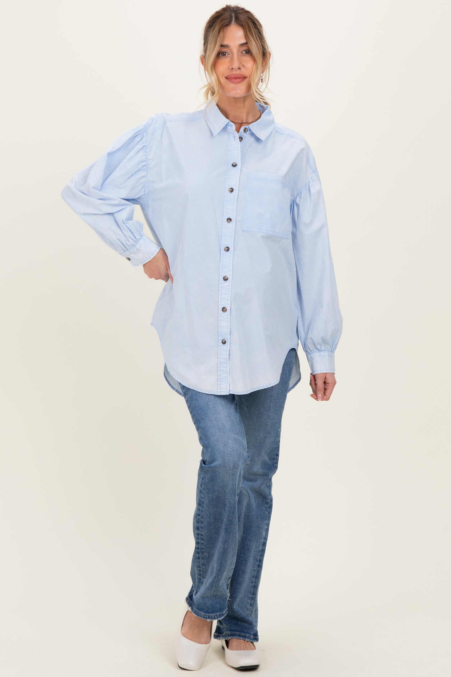 woman wearing a light blue maternity button-up shirt with puff sleeves and paired with jeans