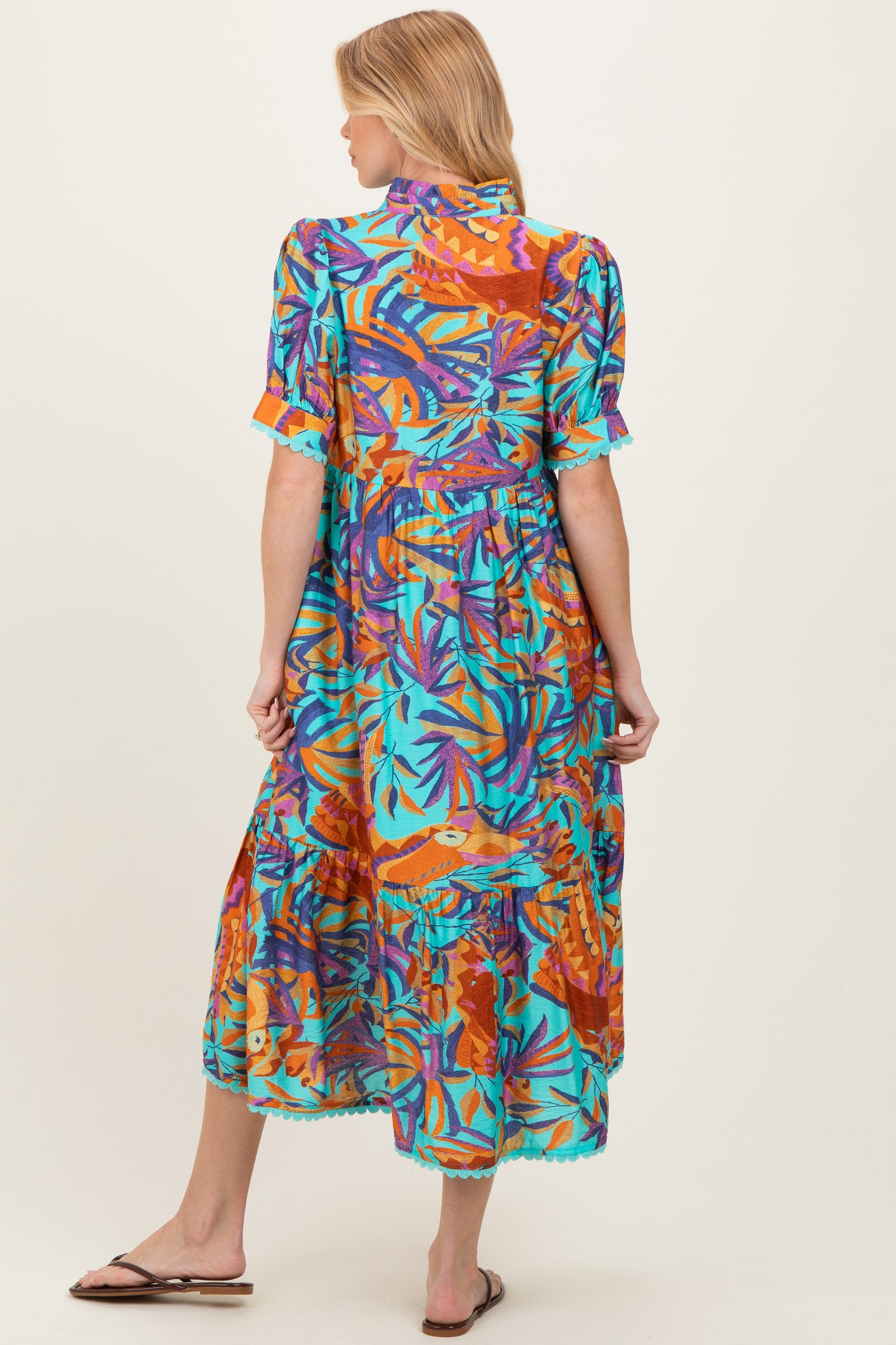 woman wearing a colorful tropical print maternity maxi dress with short sleeves and ruffled details